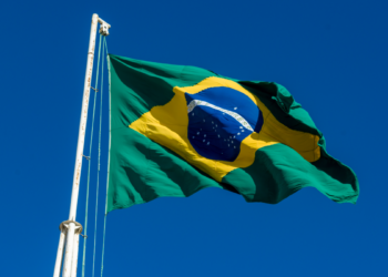 Bandeira do Brasil voando em céu azul claro.