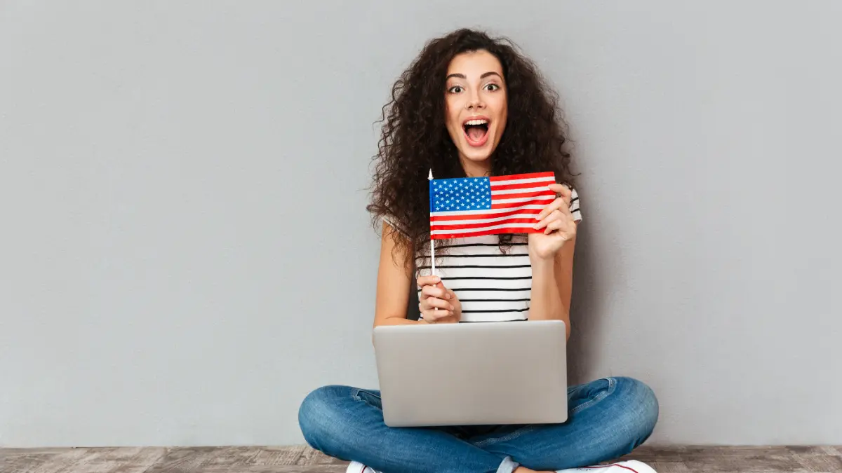 Mullher com notebook no colo e segurando bandeira dos EUA.