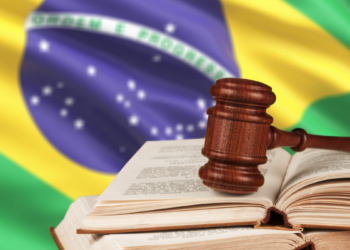 Justiça brasileira representada por martelo e livros diante da bandeira nacional.