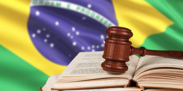 Justiça brasileira representada por martelo e livros diante da bandeira nacional.