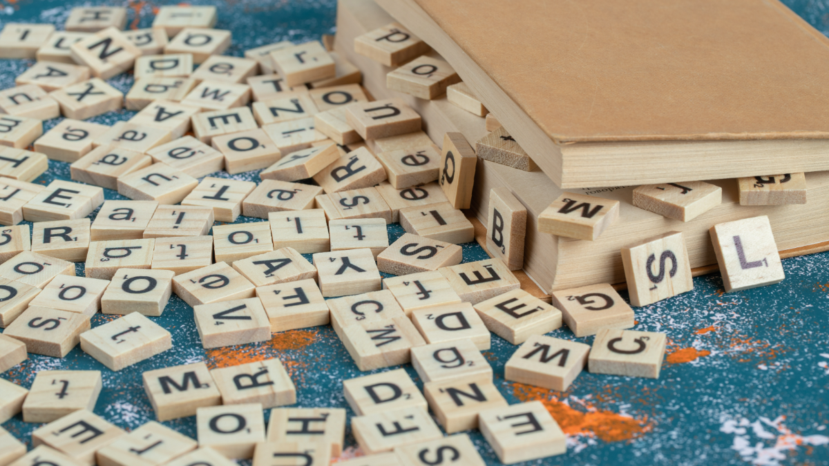 Letras de madeira espalhadas junto a livros em ambiente criativo.