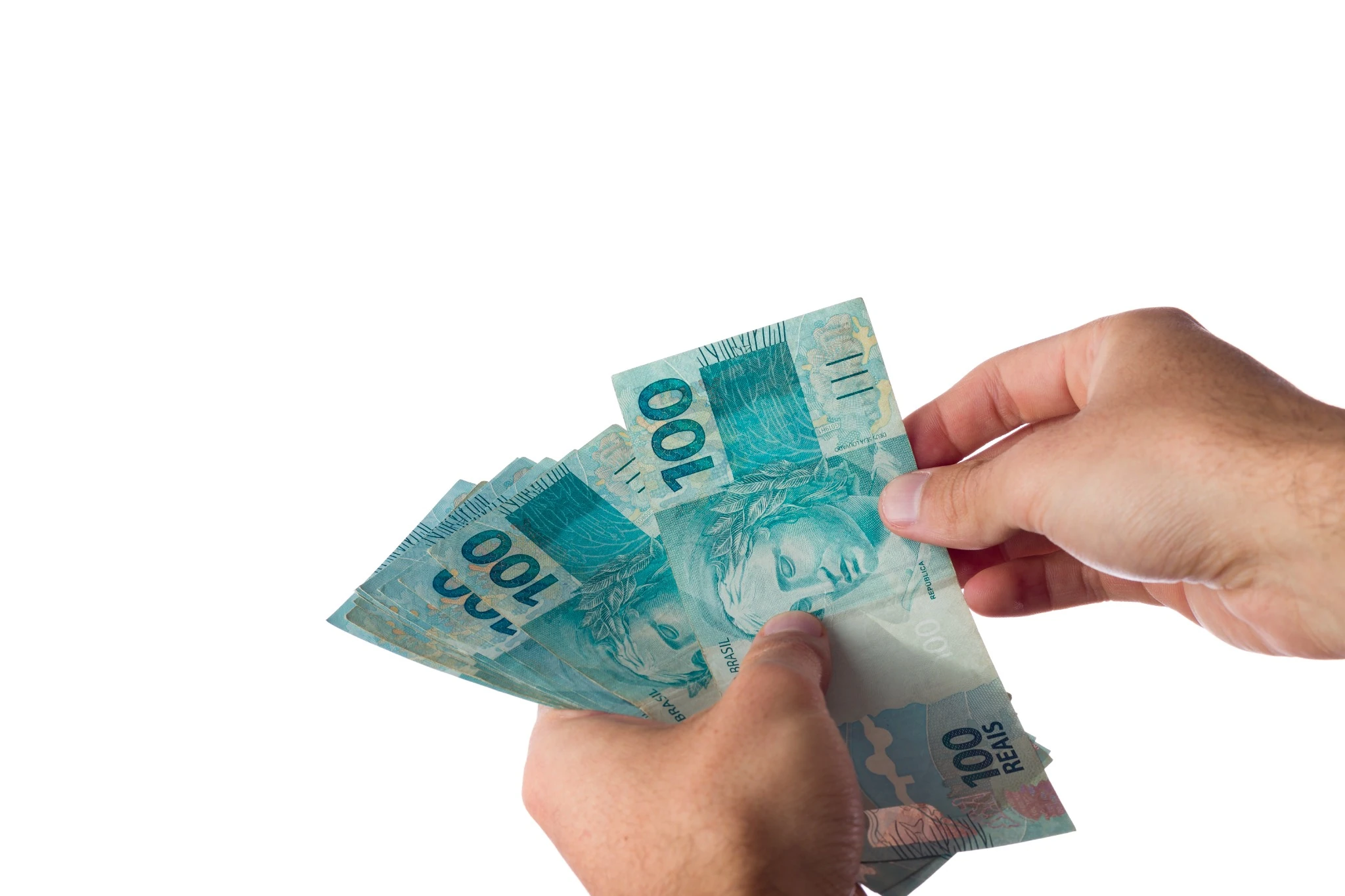 Mãos seguram cédulas de real referentes ao pagamento da restituição do Imposto de Renda.