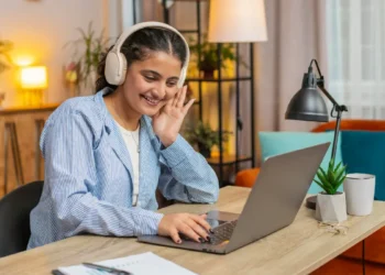 Jovem com fone de ouvido olhando para tela de notebook.
