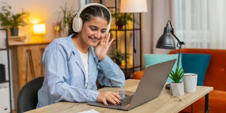 Jovem com fone de ouvido olhando para tela de notebook.