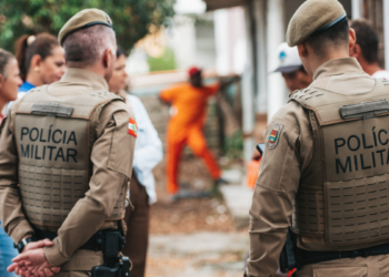 Grupo de pessoas e dois policiais militares de costas.