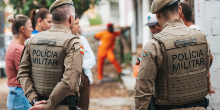 Grupo de pessoas e dois policiais militares de costas.