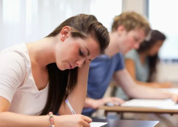 Jovens em sala de aula fazendo prova.