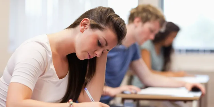 Jovens em sala de aula fazendo prova.