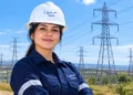 Jovem profissional usando uniforme azul-escuro e capacete da ISA Energia em uma área externa.