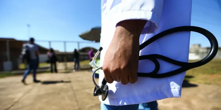 Médico segura estetoscópio enquanto representa candidatos aprovados no Revalida.