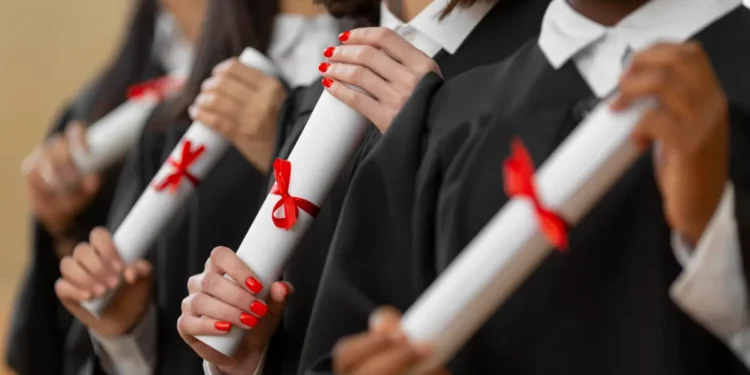 Pessoas segurando diplomas com laços vermelhos.