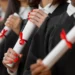 Pessoas segurando diplomas com laços vermelhos.