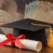 Capelo de formatura e diploma ao lado de notas de dinheiro representam aumento salarial após a graduação.