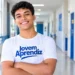 Jovem sorrindo em corredor com os braços cruzados.
