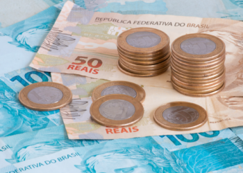 Dinheiro brasileiro em foco com notas de 50 e 100 reais e moedas.