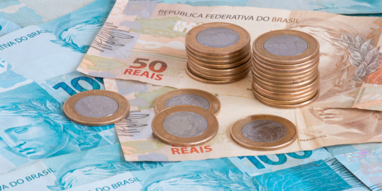 Dinheiro brasileiro em foco com notas de 50 e 100 reais e moedas.