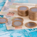 Dinheiro brasileiro em foco com notas de 50 e 100 reais e moedas.