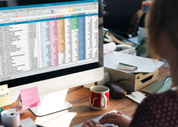 Mulher analisando planilha no Excel em ambiente de escritório.