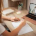 Aula online com aluna escrevendo em caderno.