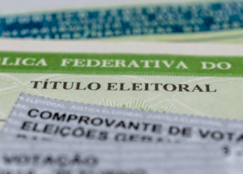 Título de eleitor brasileiro e comprovante de votação em destaque.