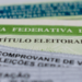Título de eleitor brasileiro e comprovante de votação em destaque.