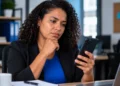 Mulher consultando informações sobre o 13º salário CLT pelo celular em ambiente de trabalho