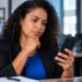 Mulher consultando informações sobre o 13º salário CLT pelo celular em ambiente de trabalho