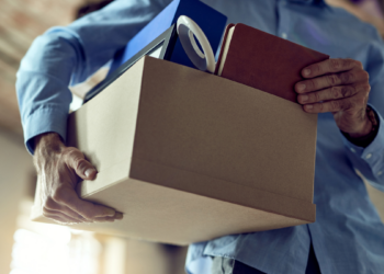 Trabalhador organizando objetos pessoais em uma caixa após encerramento de contrato de trabalho.