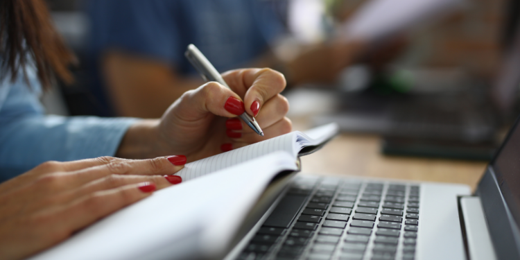Pessoa realizando anotações durante um curso livre com material de estudo e computador, representando a qualificação profissional e a diferença entre certificado e diploma.