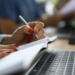 Pessoa realizando anotações durante um curso livre com material de estudo e computador, representando a qualificação profissional e a diferença entre certificado e diploma.