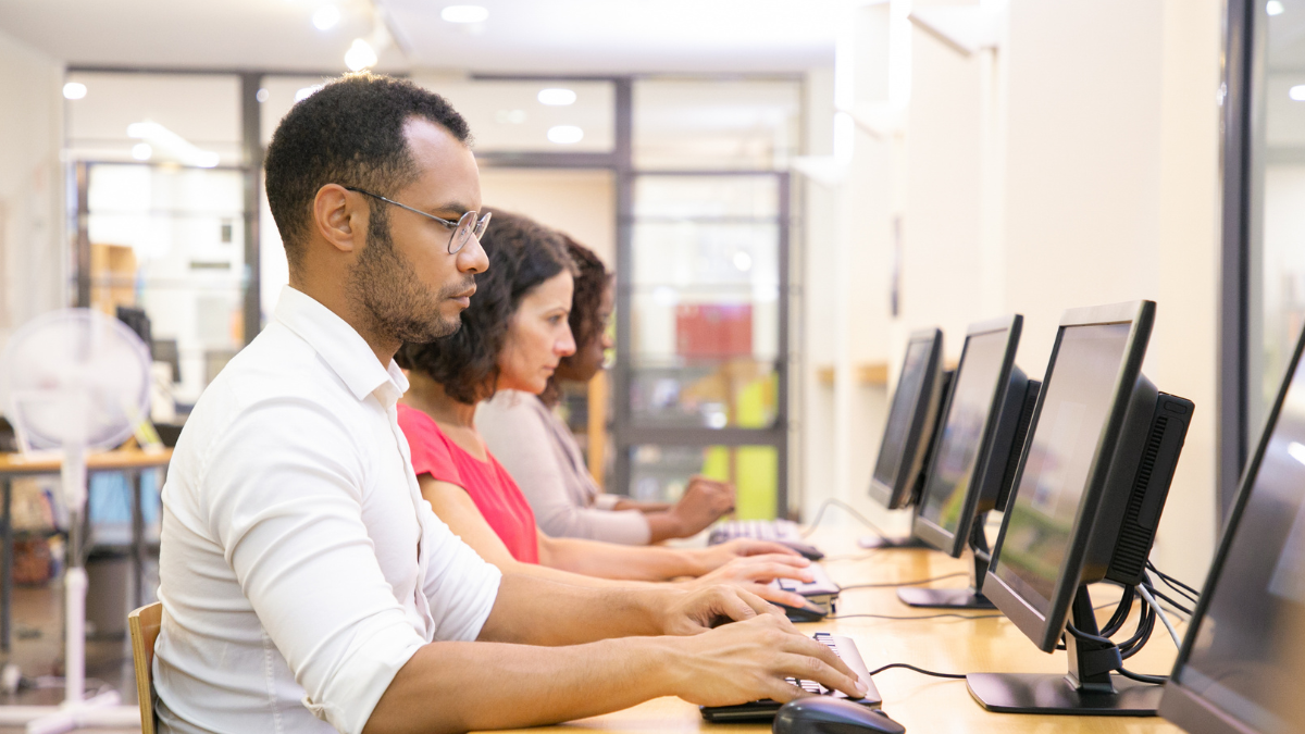 Profissionais aprendem informática em computadores durante curso de capacitação.