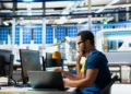 Pessoa trabalhando em ambiente industrial com computador, representando cursos técnicos e qualificação profissional em 2026.