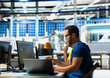 Pessoa trabalhando em ambiente industrial com computador, representando cursos técnicos e qualificação profissional em 2026.