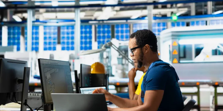 Pessoa trabalhando em ambiente industrial com computador, representando cursos técnicos e qualificação profissional em 2026.