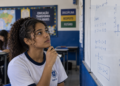 Estudante em sala de aula técnica analisando quadro com cálculos e gráficos, representando cursos técnicos para quem gosta de matemática.