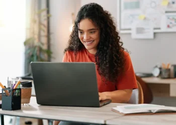 Mulher estudando curso técnico profissionalizante com notebook em ambiente de estudos.