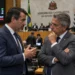 Deputados conversam em plenário durante sessão legislativa, ilustrando as diferenças entre as funções de deputado estadual e federal.