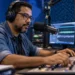 Radialista trabalha em estúdio de rádio com microfone e mesa de som durante gravação de programa