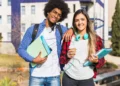 Dois estudantes com livros em frente a uma universidade representam graduações apontadas como algumas das mais valiosas do mercado.