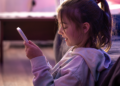 Criança utilizando celular em ambiente doméstico representando o uso da internet por menores de idade.