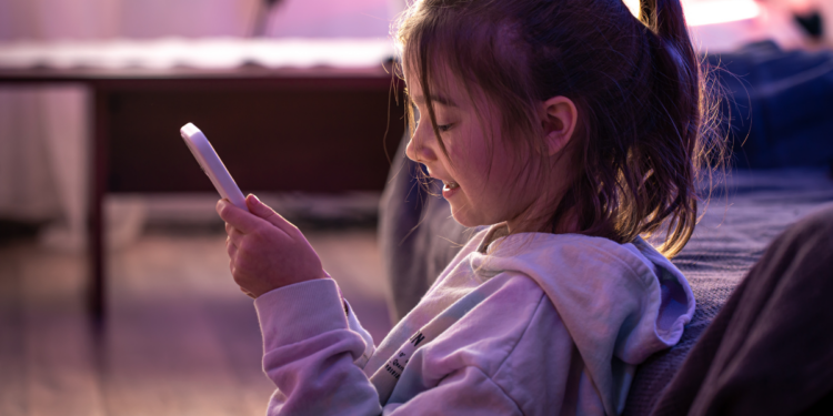Criança utilizando celular em ambiente doméstico representando o uso da internet por menores de idade.