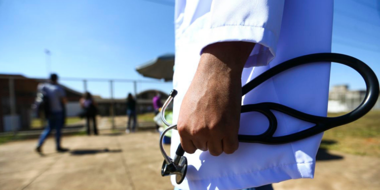 Médico segurando estetoscópio representa o Enamed, exame nacional de avaliação da formação em medicina.