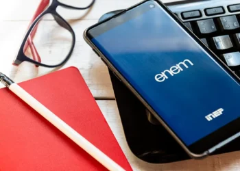 Celular com aplicativo do Enem ao lado de materiais de estudo representa a preparação para a prova de 2026.