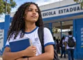 Estudante em frente a uma escola representa os desafios para a conclusão do ensino médio no Brasil.