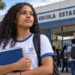 Estudante em frente a uma escola representa os desafios para a conclusão do ensino médio no Brasil.
