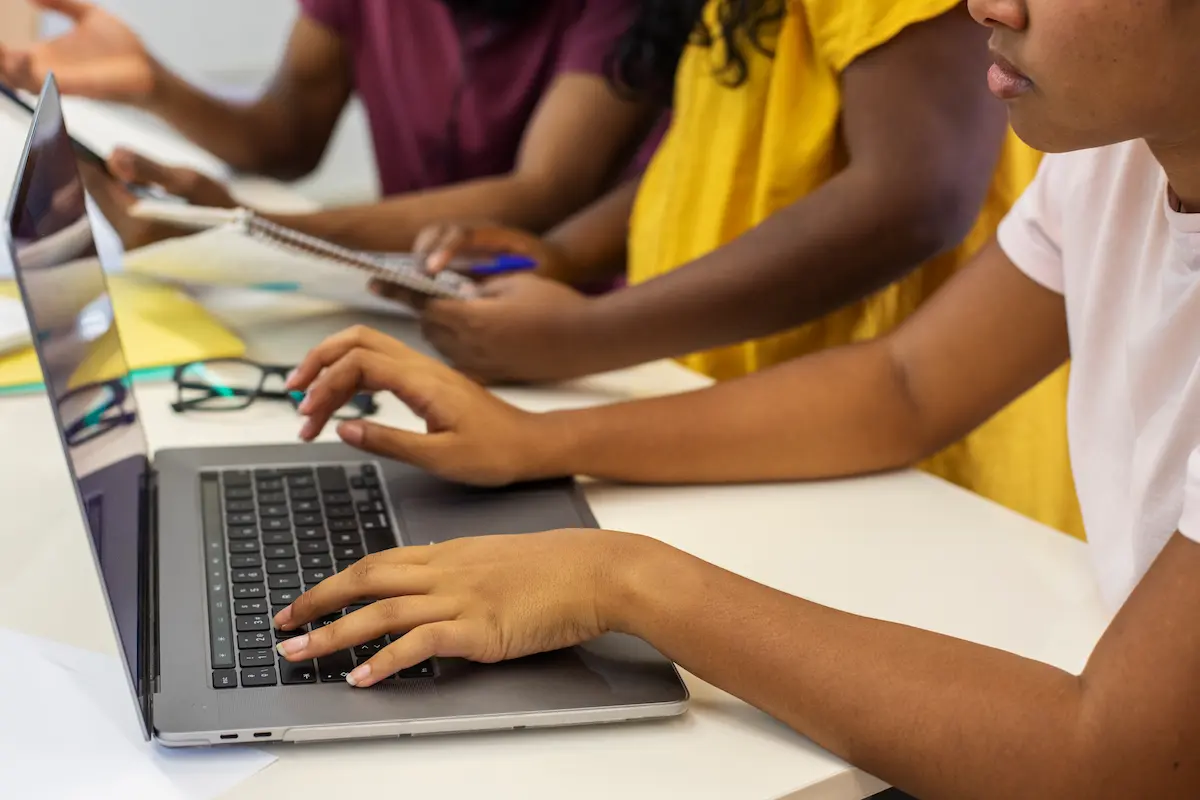 Estudantes utilizando notebook durante atividade de pesquisa e cadastro online para oportunidades de estágio.