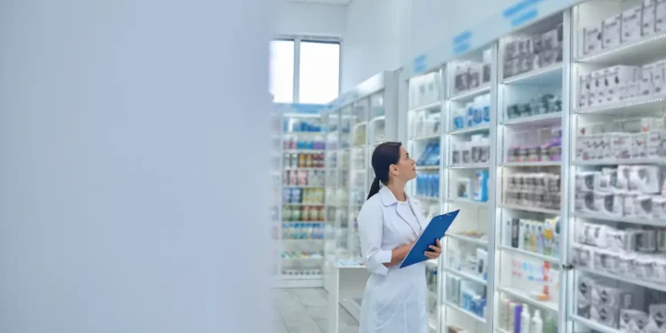 Farmacêutica organiza medicamentos em farmácia durante o Dia Internacional do Farmacêutico.