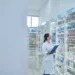 Farmacêutica organiza medicamentos em farmácia durante o Dia Internacional do Farmacêutico.