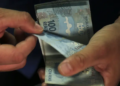 Mãos contando cédulas de cem reais, representando o valor liberado no saque do FGTS aos trabalhadores que cumprem os critérios.