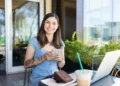 Mulher com celular ao lado de notebook representa acesso ao Fies Empreendedor para contratação de crédito.